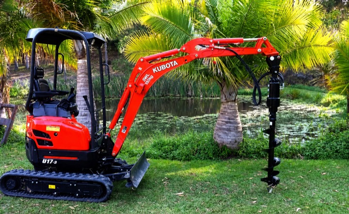 Compact red Kubota excavator with a long auger attachment