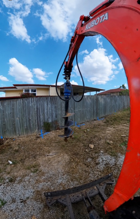 Kubota excavator drilling post holes with an auger attachment