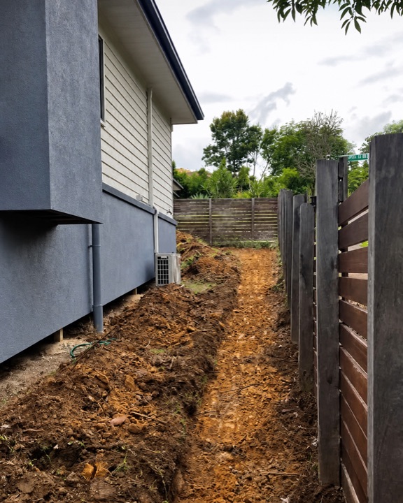 Fresh trench excavated through a narrow side access beside a Brisbane home